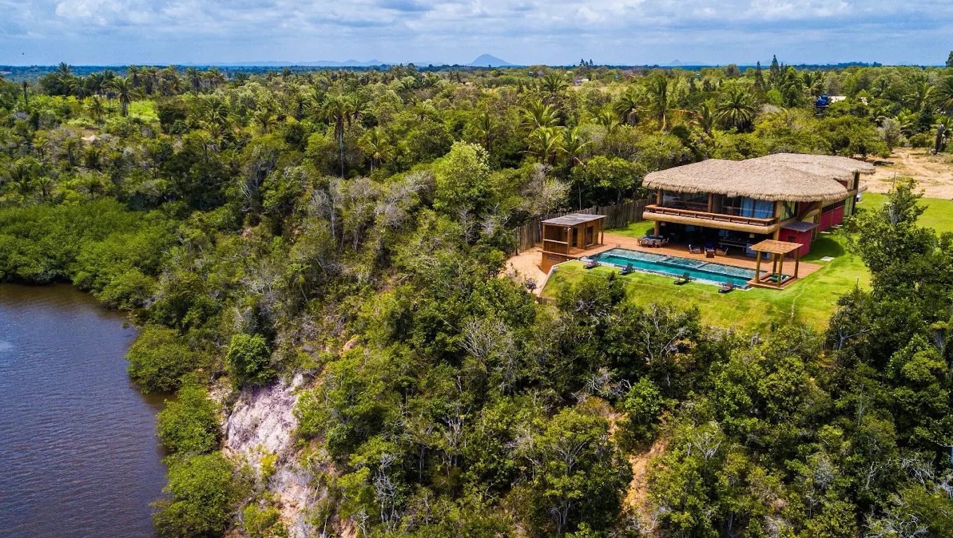 Vista aérea da casa com a piscina, o rio e o mar