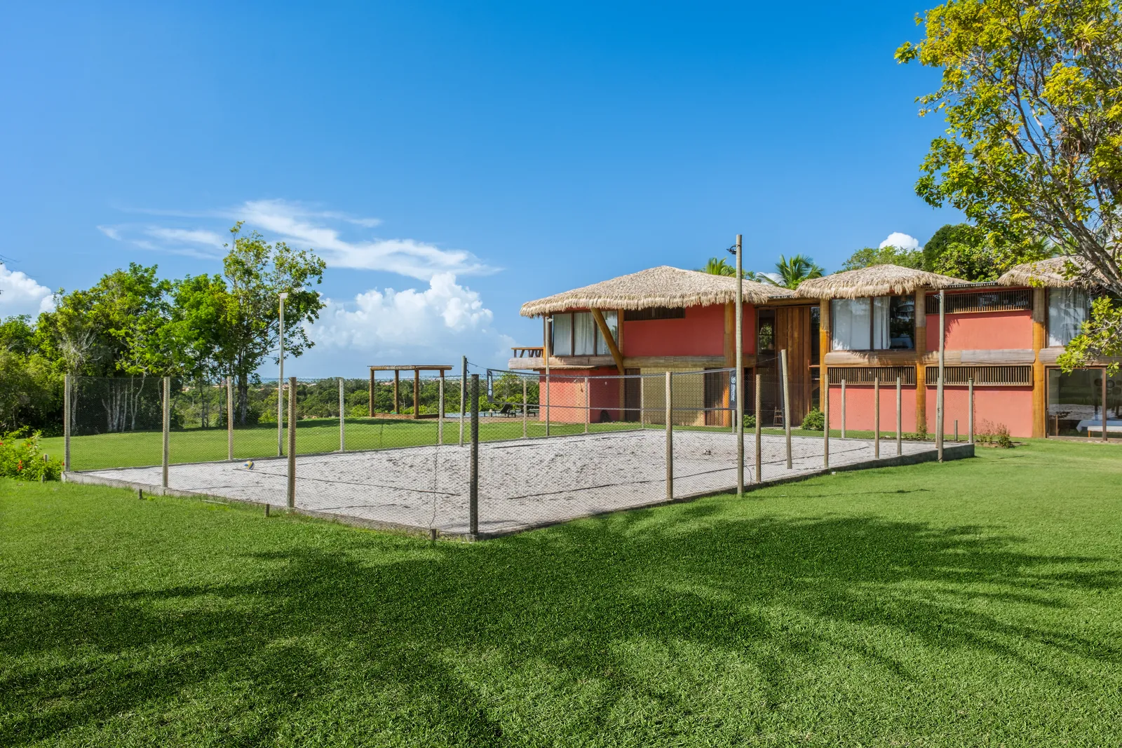Quadra de areia no gramado, com a casa ao fundo